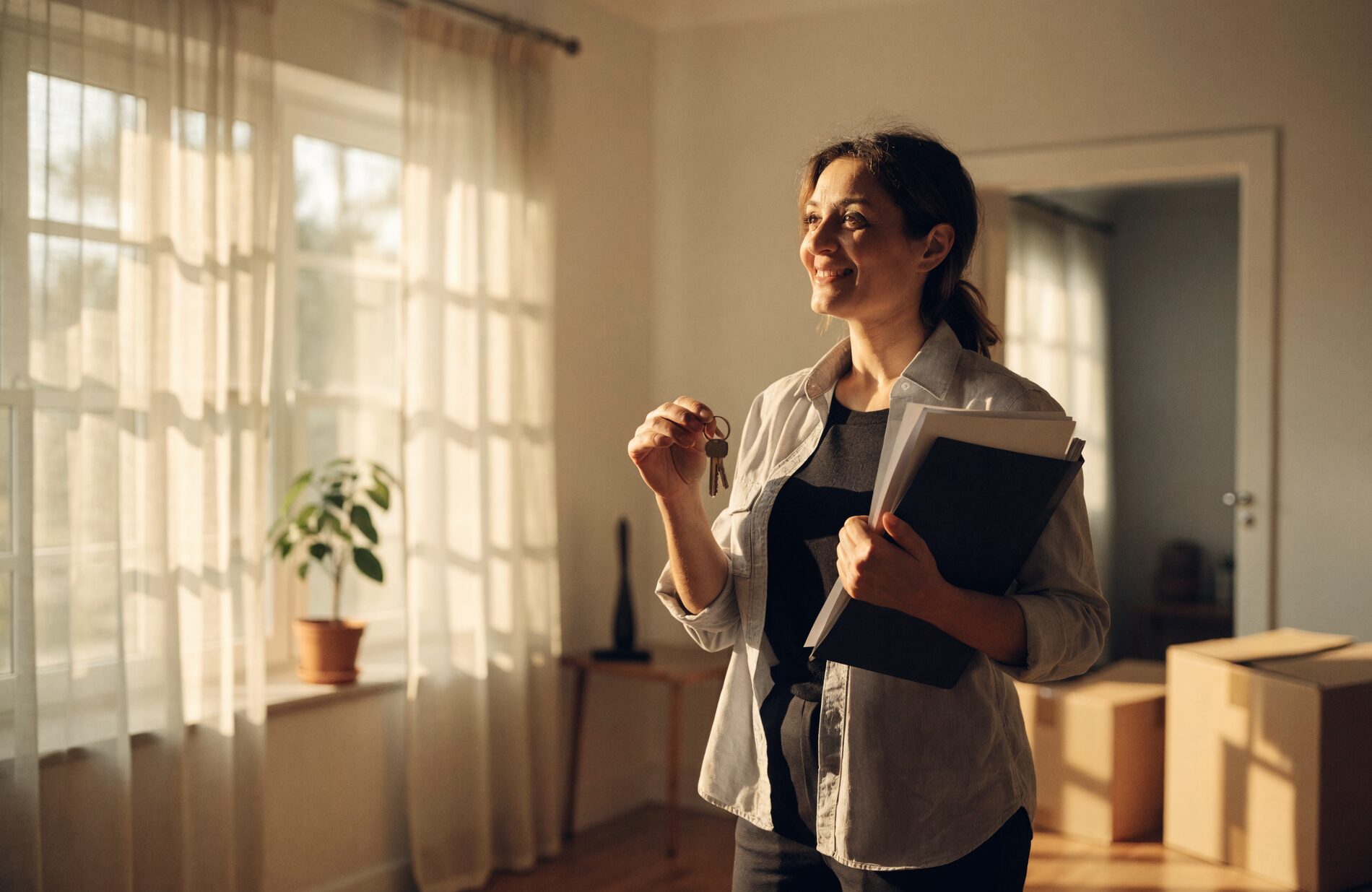 A landlord holding keys in the bright, freshly prepared living room of a rental home